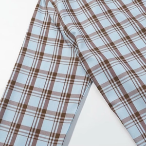 Gros plan du tissu popeline à carreaux bleu clair et fauve avec détails de couture