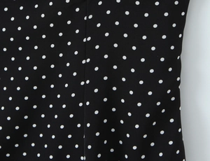 Detailed close-up of high-quality black and white polka dot fabric with seam stitching