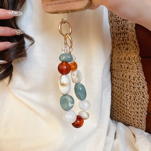 Detailed shot of irregular resin beads phone charm with vintage amber and sage green marbling