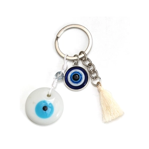 Macro shot of evil eye keychain with silver ring, beaded charms and off-white cotton tassel