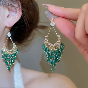 Detailed view of bohemian gold water drop tassel earrings with green crystal beads