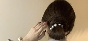 Elegant pearl hair tie worn on a low bun, featuring gradient white pearls for styling