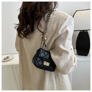 Close-up of black quilted mini bag with gold chain strap and spherical charm detail