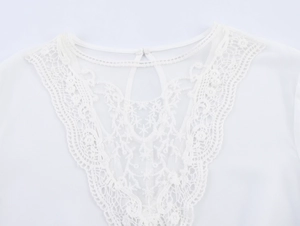 Detailed close-up of white chiffon top with floral lace neckline and cutout embroidery