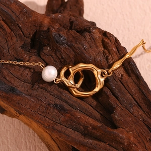 Détail du collier à double anneau plaqué or 18K avec une perle sur une texture de bois