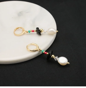 Macro detail of vintage 18k gold plated earrings with baroque pearl and black onyx stone