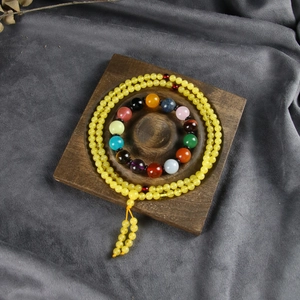 Detail view of colorful natural stone beads and yellow prayer beads on a wooden tray