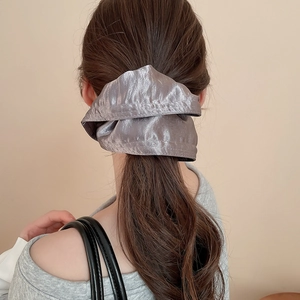 Detail view of a large dusty purple satin scrunchie on a low ponytail with silky texture