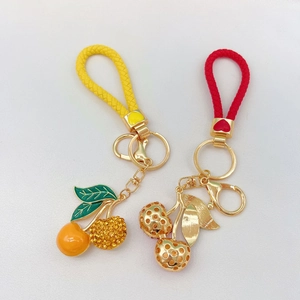 Detailed view of cherry keychains with rhinestones, enamel leaves, and woven ropes