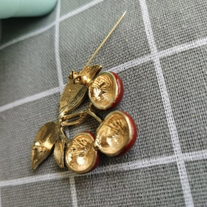 Vue arrière détaillée de la broche cerise montrant l'épingle et la texture dorée