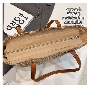 Detail view of woven straw tote bag featuring brown leather handles and a metal zipper