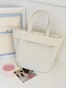 Close-up of minimalist cream canvas tote bag with unique folded edge and dual handles