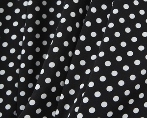 Détail de tissu vintage noir à pois blancs avec texture plissée et souple