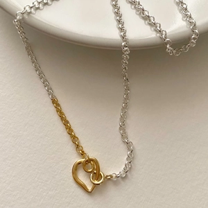 Minimalist 925 sterling silver heart necklace with interlocking gold rings on ceramic