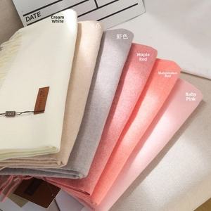 Detailed view of multi-color cashmere feel scarves with elegant tassels and leather logo