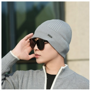 Detailed texture of light gray ribbed knit beanie with small metallic logo plate