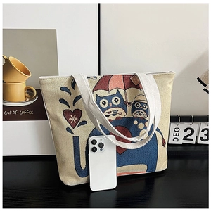 Detail of woven owl pattern on beige canvas tote bag with smartphone for scale