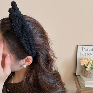Detail of a black plush bow headband showing the soft texture and high crown styling