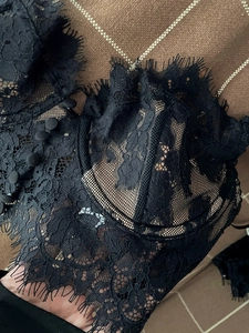 Detail view of black eyelash lace lingerie featuring intricate floral embroidery and buttons