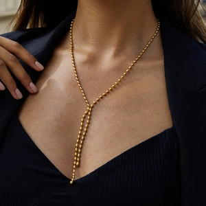 Elegant gold stainless steel beaded Y-necklace with tassel drop on a female model
