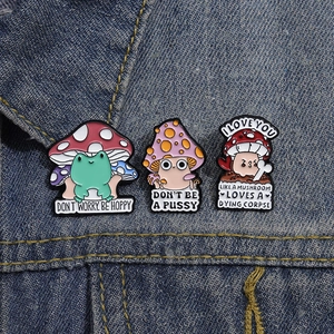 Close-up of cute mushroom and frog enamel pins on denim with Don't Worry Be Hoppy text