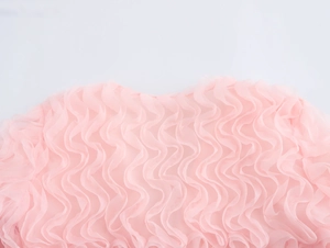 Détail du tissu en maille rose avec texture plissée et design à col en V à volants