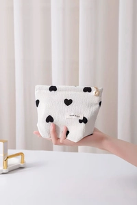 Detail of seersucker heart pouch showing white fabric texture and gold flower zipper pull