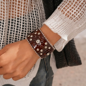 Détail d'un large bracelet en cuir bohème avec strass facettés et bordure de perles en métal