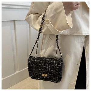 Close-up of black tweed flap bag with gold chain strap worn over a beige coat