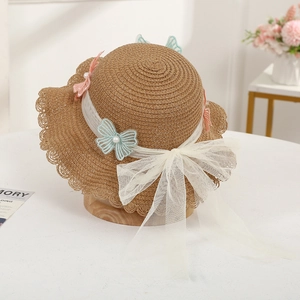 Detail of child straw hat with butterfly embroidery and white mesh bow decoration