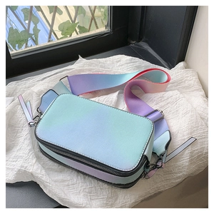 Detail of colorful gradient camera bag with wide strap and dual zippers on white cloth