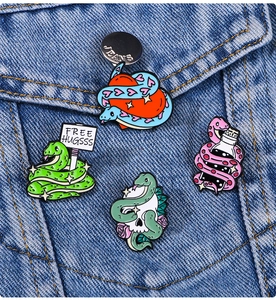 Detailed close-up of 4 cartoon snake enamel pins on a blue denim jacket pocket