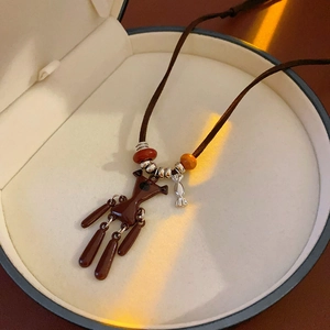Close-up of brown bear necklace with orange beads and silver charms in a jewelry box