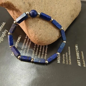 Detailed close-up of a blue lapis lazuli beaded bracelet on a natural stone base