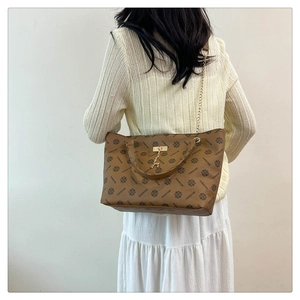 Detail of vintage tote bag with metal chain strap and decorative golden deer charm