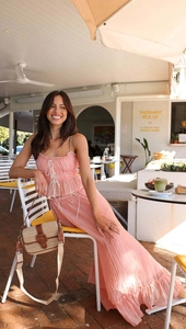 Detail of pink pleated camisole set paired with a straw crossbody bag in a street cafe