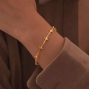 Detail of a minimalist gold star bracelet on a model wrist with vintage matte texture