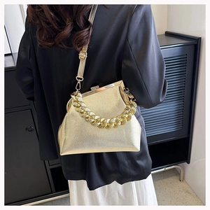 Detail showing metallic gold lychee leather texture and chunky chain handle on small bag