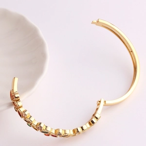 Detailed close-up of 18K gold plated geometric bangle with colorful zircon crystals