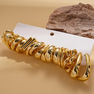 Close-up of golden geometric hoop earring set in various shapes on warm background