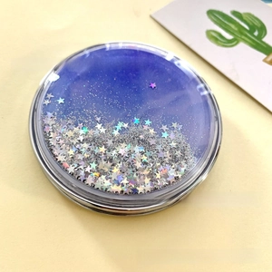 Detail of round folding makeup mirror featuring blue liquid quicksand and silver sparkles