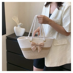 Close-up of woven cotton tote bag featuring pink bow decoration and metal ring detail