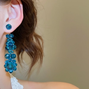 Close-up of elegant long blue crystal flower tassel earrings worn by a model