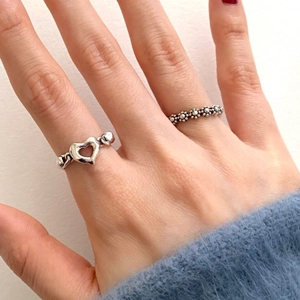 Macro detail of S925 sterling silver heart ring and vintage flower band on fingers