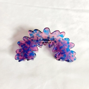 Détail de la pince à cheveux en acétate marbré avec design ondulé et ressort métal