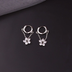Detailed view of silver flower earrings with zircon petals and black center on dark background