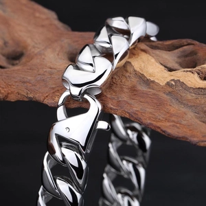 Détail macro d'un bracelet gourmette en acier argenté sur bois avec fermoir homard