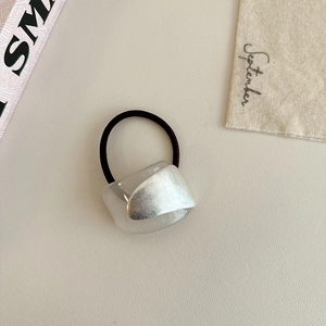 Detailed shot of silver metal plate and acrylic geometric bead on black elastic hair tie