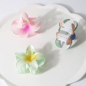 Three gradient frangipani hair claw clips on a white tray, floral hair accessories for women