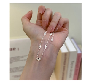 Detail of s925 silver flower bracelet with five hollow floral charms on woman's wrist